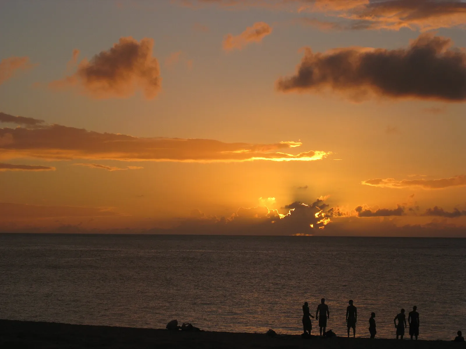 ワイメア湾に沈む夕日を見る人たち